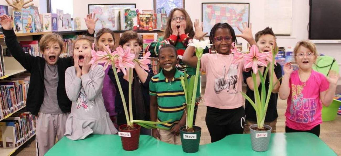 students posing with their amaryllis plant from the library